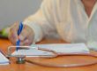 une personne écrit sur un papier avec un stéthoscope au premier plan
